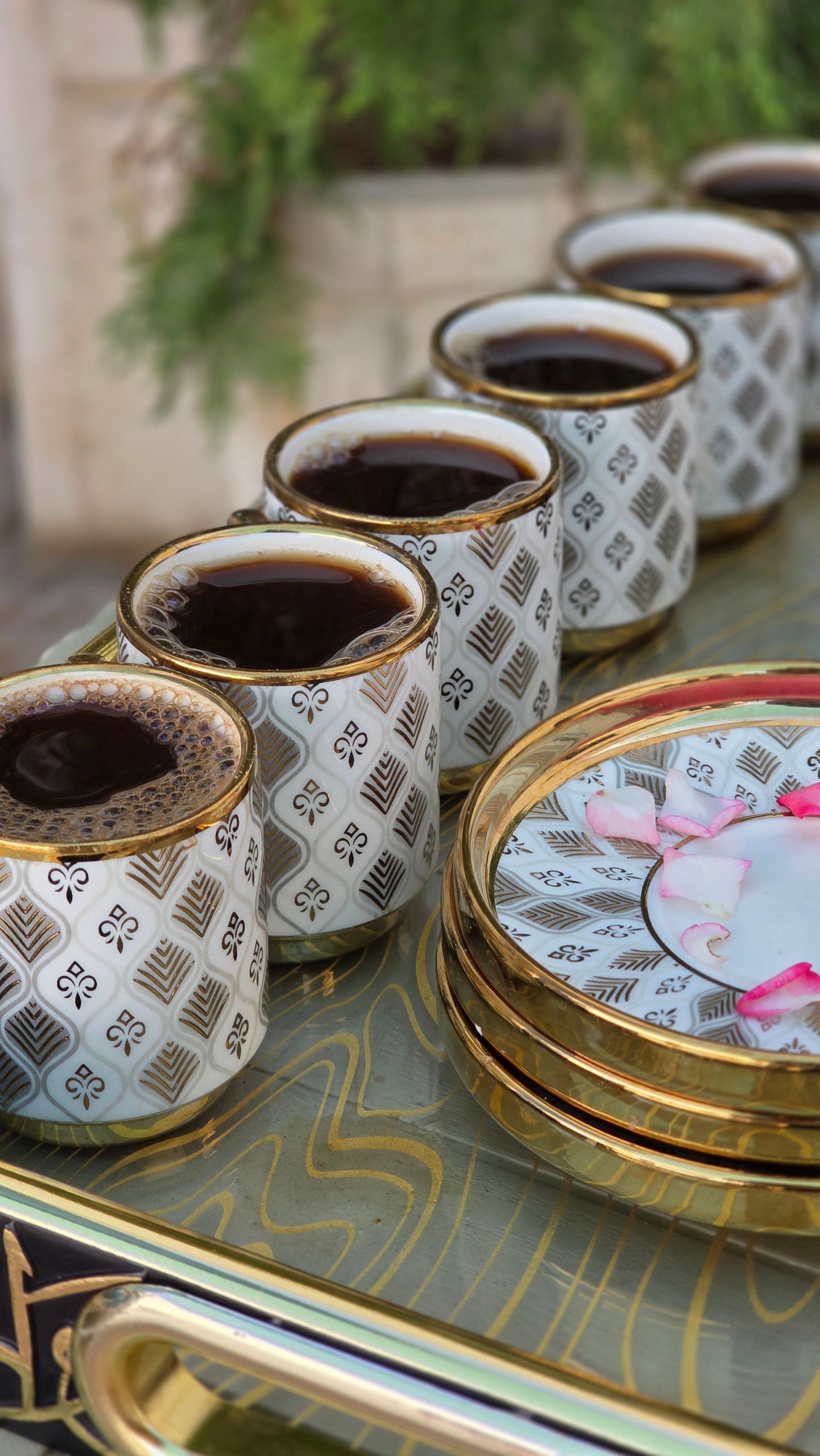 Stylish Arabic coffee cups arranged on a decorative tray outdoors.